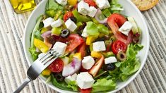 a salad with tomatoes, olives, lettuce and feta cheese on it