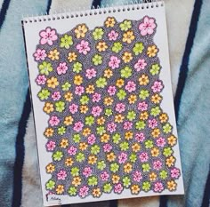 a notebook with flowers on it sitting on top of a blanket