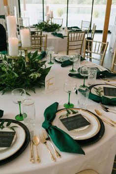 the table is set with place settings and green napkins on it, along with candles