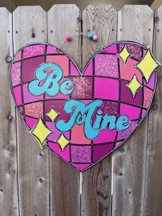 a heart shaped sign with the words be mine painted in blue and pink on it