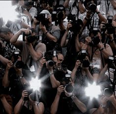 a large group of people holding up cameras and taking pictures with their cell phones in front of them