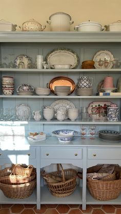 a china cabinet filled with lots of dishes and baskets on top of it's shelves