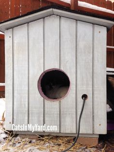 a cat house with a hose attached to it's side and snow on the ground