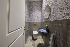 a bathroom with purple and white wallpaper, toilet and sink in the corner next to each other