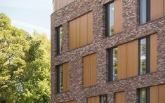 a tall brick building with many windows next to trees