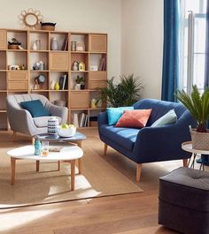 a living room filled with furniture next to a window and bookshelf full of shelves