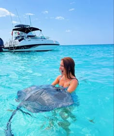 a woman is in the water with a stingfish near her and boats behind her