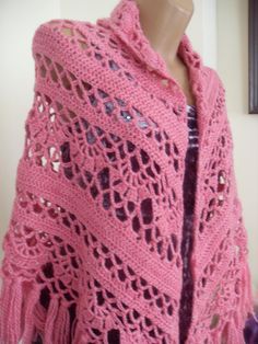 a pink crocheted shawl is shown on a mannequin