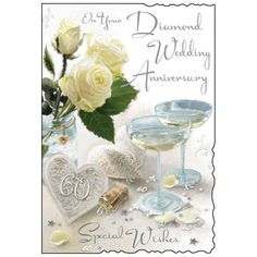 a wedding anniversary card with champagne glasses and white roses in the center, on a table