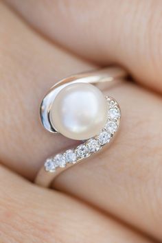 a woman's hand with a pearl and diamond ring