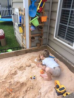 a little boy playing in the sand with toys