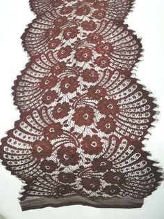 a piece of lace with red flowers and leaves on the edge is sitting on a white surface