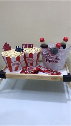 two trays filled with popcorn and drinks on top of a white table next to each other