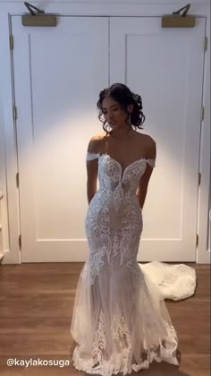 a woman in a wedding dress standing on the floor with her hands on her hips