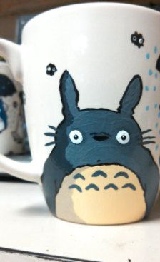 a totoro coffee mug sitting on top of a table next to another cup