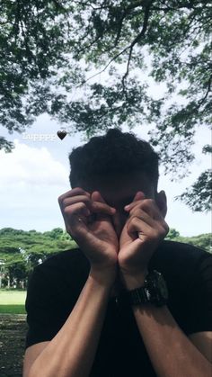 a man holding his hands to his face in front of a tree with the words happy on it