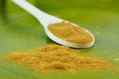 a spoon filled with brown powder sitting on top of a green plate