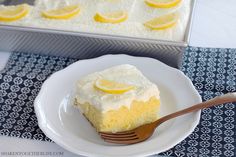 a piece of cake on a plate with a fork next to it and a pan of lemons in the background