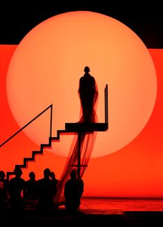 the silhouette of a man and woman standing on stairs in front of an orange sun