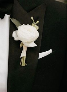 a man in a tuxedo wearing a boutonniere with white flowers