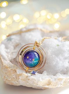 Experience the cosmic allure of our Galaxy Necklace, an exquisite celestial jewelry piece inspired by the intricate orbits of our planetary system. This unique accessory features three brass rings, elegantly nested within each other, capturing the essence of galactic paths traced in the vast expanse of space. If you're an aficionado of astronomy, galaxies, and the mysteries of outer space, this spinning necklace is your ideal accessory. At the heart of this piece lies a handmade ball, delicately Necklace Planet, Spinning Necklace, Space Necklace, Saturn Necklace, Astronomy Science, Galaxy Necklace, Science Jewelry, Planet Necklace, Celestial Necklace