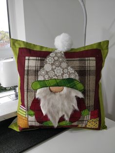 a decorative pillow with an image of a gnome's head on it and a white pom - pom in the corner