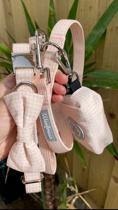 a hand holding a pink and white checkered bow tie keychain with two metal rings