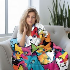 a woman is sitting on a couch with a colorful cat blanket in front of her