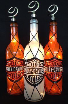 three bottles with lights in them sitting next to each other on a black table top