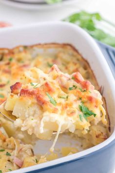 a casserole dish with ham and cheese being lifted from the casserole