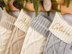 three christmas stockings hanging from a wooden rack with pine cones and evergreen needles on it