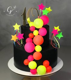 a black cake with neon colored stars and balloons