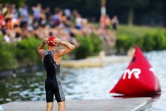 a man standing on top of a dock next to a red object in the water