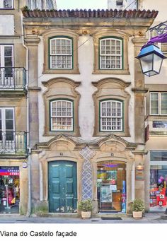 an old building with many windows and shutters on the front, along side a street