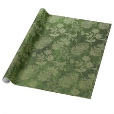 a green and gold wallpaper with floral design on the bottom, is rolled up to look like a roll of paper