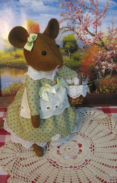 a stuffed mouse is sitting on a doily