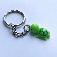 a keychain with a green turtle on it's side and a silver ring