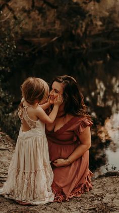 a mother and her daughter are sitting by the water