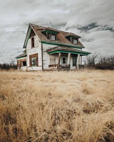 an old abandoned house sitting in the middle of a field with no grass on it