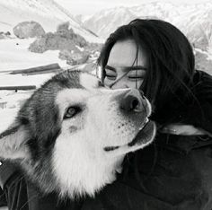 a woman is hugging her dog in the snow