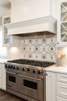 a stove top oven sitting inside of a kitchen next to white cabinets and counter tops