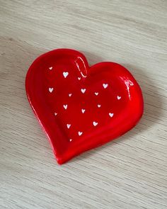 a red heart shaped dish sitting on top of a wooden table