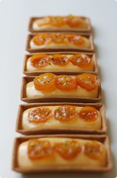 small slices of food arranged in rows on a white counter top with orange toppings