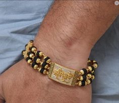 The Mahadev Design Gold Plated Rudraksha Bracelet is a timeless accessory for men. Crafted from brass and plated with gold, this textured design features diamond etching, a shining Rudraksha bead, and a black-hued bracelet for a spiritual yet stylish look. 100% Hid_Reg_Plating ensures lasting shine and durability. Bracelet Dimension Height:20 cm (7.87 inch) Width:17 mm (1.7 cm) Depth:3 mm (0.3 cm) Other Specification Weight:20 Gram Size:Fixed Lock Type:Fold Over / Flap Over Color:Golden, Black M Bollywood Style Bracelets With Latkans As Gift, Traditional Latkans Bracelets For Diwali, Festive Latkans Bracelets As Gift, Handmade Bracelets For Navratri Celebration, Traditional Festive Bracelets For Puja, Diwali Rituals Bracelet With Latkans, Festive Celebration Bracelets With Latkans, Bollywood Style Bracelets For Navratri Rituals, Cutdana Bracelets For Puja And Navratri