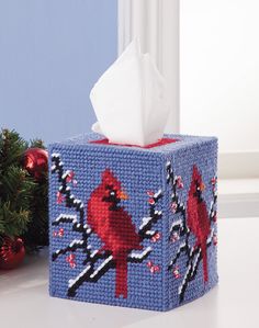 a tissue box with a cardinal design on it and a christmas tree in the background