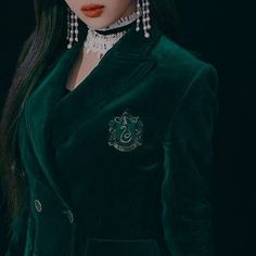 a close up of a doll wearing a green suit and necklace with white pearls on her head