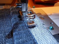 the sewing machine is working on the blue material that has been sewn together with it's needle