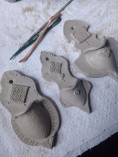 three pieces of pottery sitting on top of a white towel next to a pair of scissors