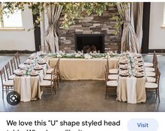 the table is set up in front of the fireplace for an elegant wedding reception with white linens and greenery