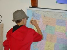 a man in a hat writing on a map